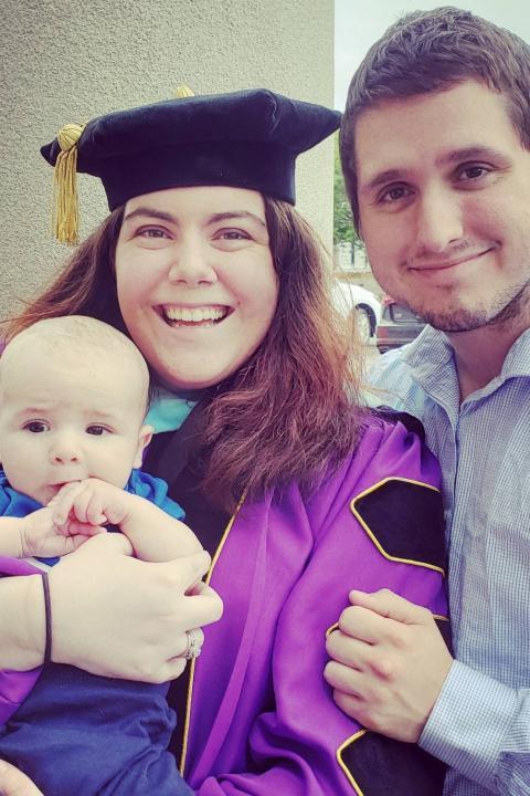 艾利森·普拉茨米耶穿着毕业装站在搭档身边，手里抱着孩子